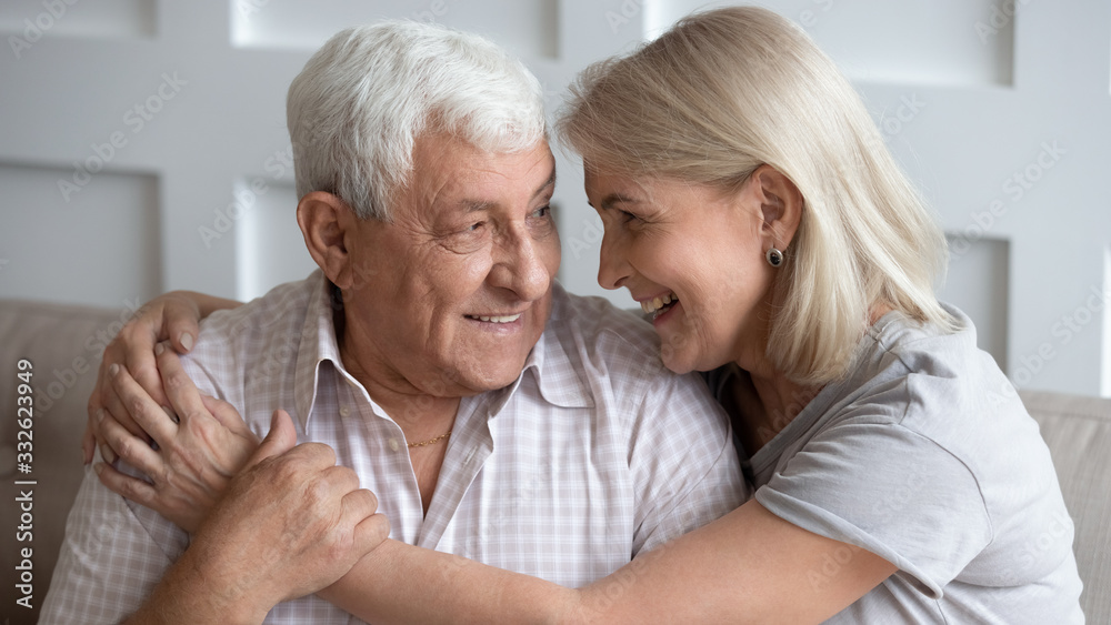 Happy older wife and husband hugging, looking in eyes, expressing love and support, family enjoying tender moment together, sitting on cozy sofa, mature father and middle-aged daughter close up Happy older wife and husband hugging, looking in eyes, expressing love and support, family enjoying tender moment together, sitting on cozy sofa, mature father and middle-aged daughter close up