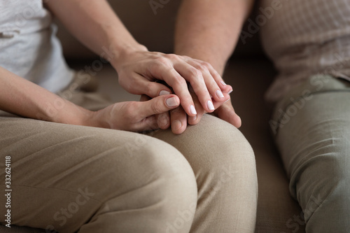 Close up middle-aged woman wife holding older man husband hands, expressing love and empathy, adult daughter helping elderly father to overcome problems, caregiver consoling and supporting patient
