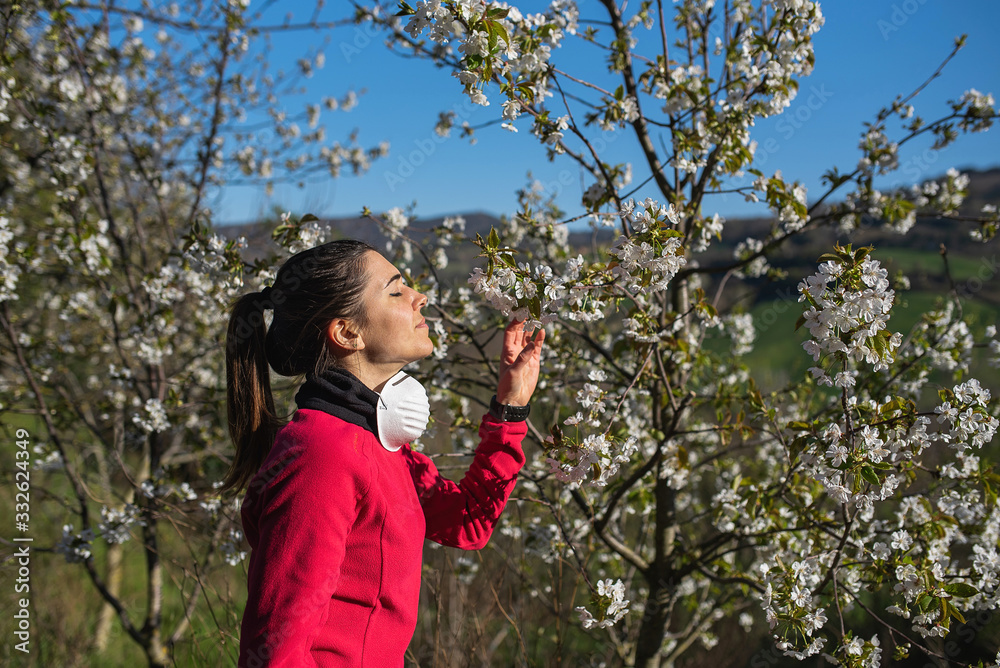 woman take off mask as coronavirus prevention to smell cherry flowers woman take off mask as coronavirus prevention to smell cherry flowers