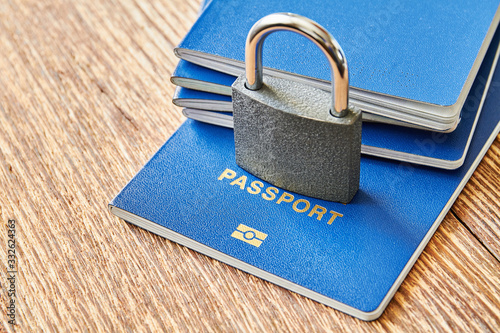 A padlock and passports on the wooden surface. Coronavirus and travel concept. Closing borders between countries due to virus. Closeup photo