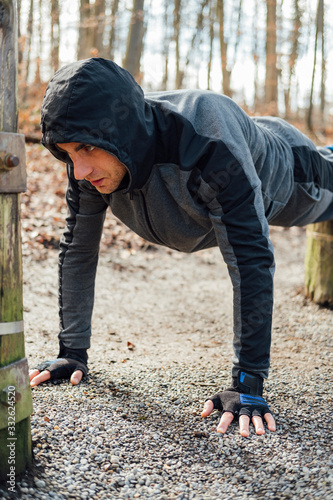 Young man wearing hoodie workout in the forest park. 