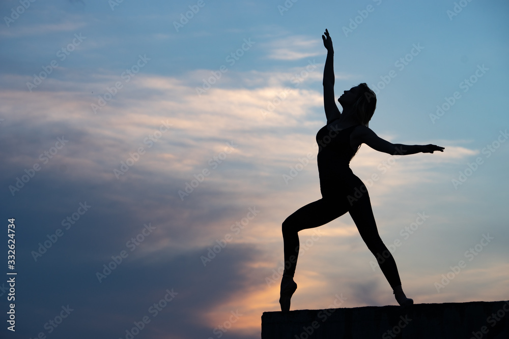 Well shaped woman dancer on outdoor sunrise background. Concept of freedom and happy lifestyle