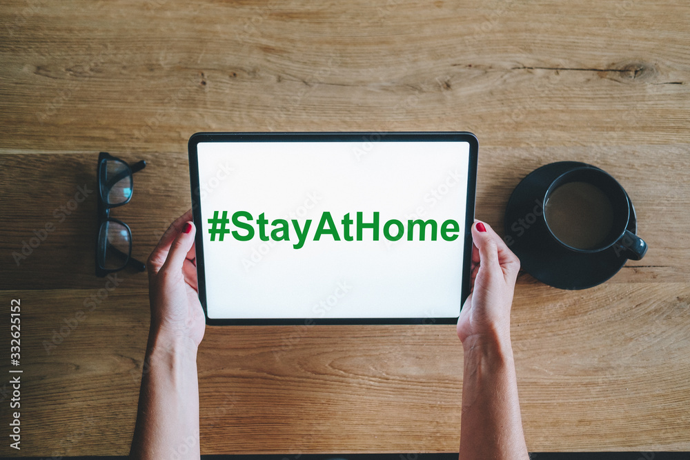 A digital tablet with hand, with the text Stay at home on the screen A digital tablet with hand, with the text Stay at home on the screen