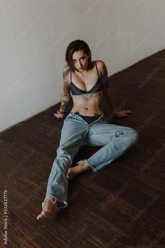 Fototapeta premium Sexy tattooed woman wearing underwear and jeans