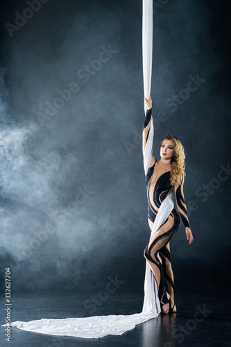 A young girl performs the acrobatic elements in the airrial silk. Studio shooting performances on a black background