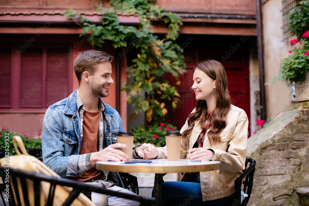 Selective focus of couple with disposable cups of coffee in cafe in city Selective focus of couple with disposable cups of coffee in cafe in city
