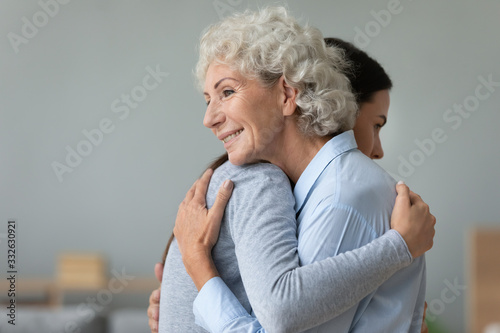 Happy elderly mom and grown-up daughter hug embrace make peace after fight, supportive mature mother and adult girl child cuddle reconcile share close intimate moment support concept