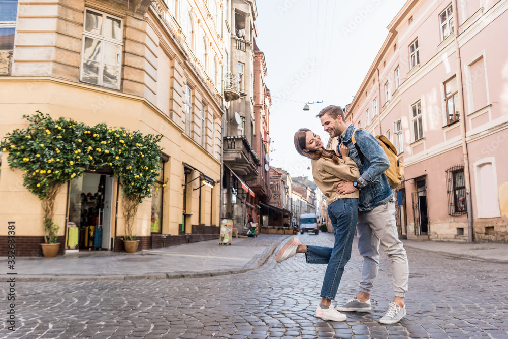 Selective focus of couple having fun and looking at each other in city