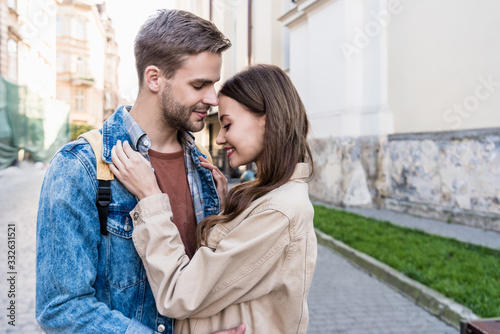 Selective focus of couple hugging and smiling in city