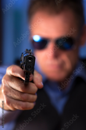 Criminal businessman aiming a pistol a at the viewer
