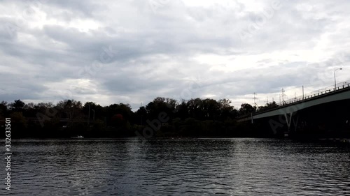 Wallpaper Mural Motion time lapse view of boats and rowing teams practicing on a calm river as clouds roll across the sky. People enjoy watersports on a warm afternoon. Boats pass under bridge. PAN RIGHT. Torontodigital.ca