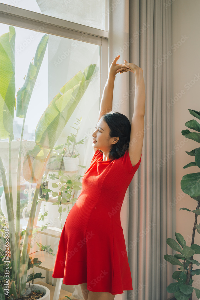 Beauty pregnant woman stretching her hand near the window Beauty pregnant woman stretching her hand near the window