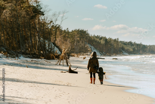 Mom walks with a small child on the beach