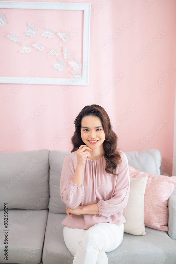 Portrait of an Asian woman laughing and smiling when sitting on sofa. Portrait of an Asian woman laughing and smiling when sitting on sofa.