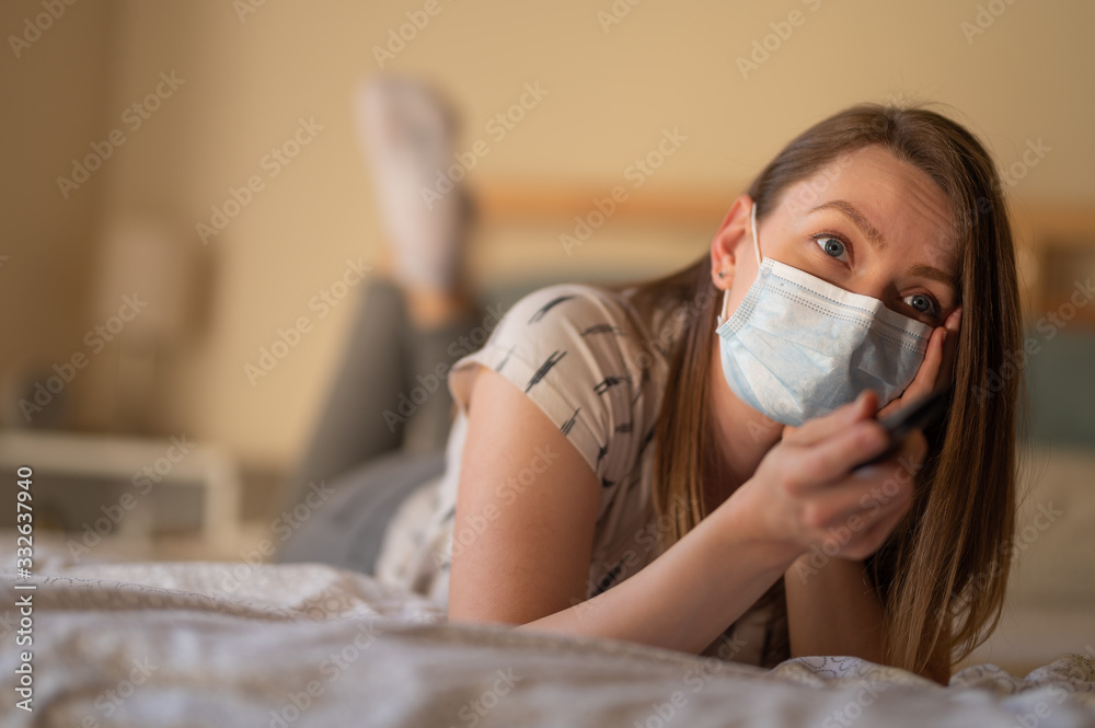 A girl in quarantine with a mask watches TV. Rest in quarantine and keeping it at home. Coronavirus and the danger from it A girl in quarantine with a mask watches TV. Rest in quarantine and keeping it at home. Coronavirus and the danger from it