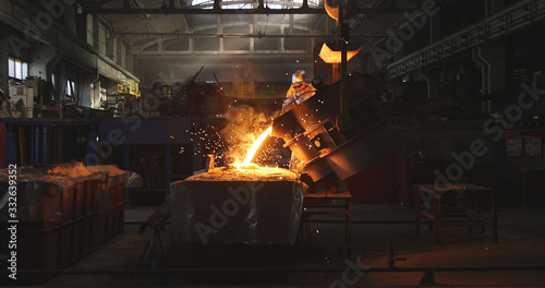 Smelting metal in a metallurgical plant. Liquid iron from metal ladle pouring in castings at factory