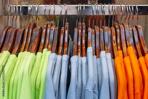 Multi-colored women's sweaters on wooden hangers, concert of clothing selection.