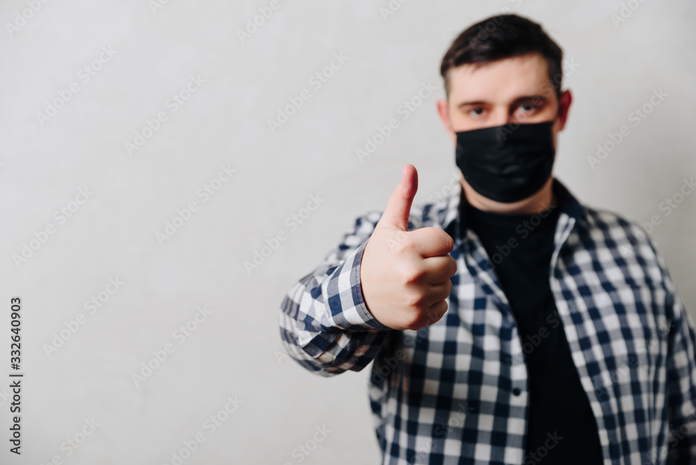 man in a shirt in a black medical mask on a gray background