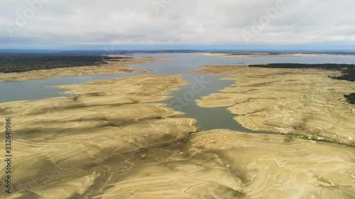 Flying over Lake in Sardon small village in Spain next to amazing unique Lake with yellow sand and blue water. photo