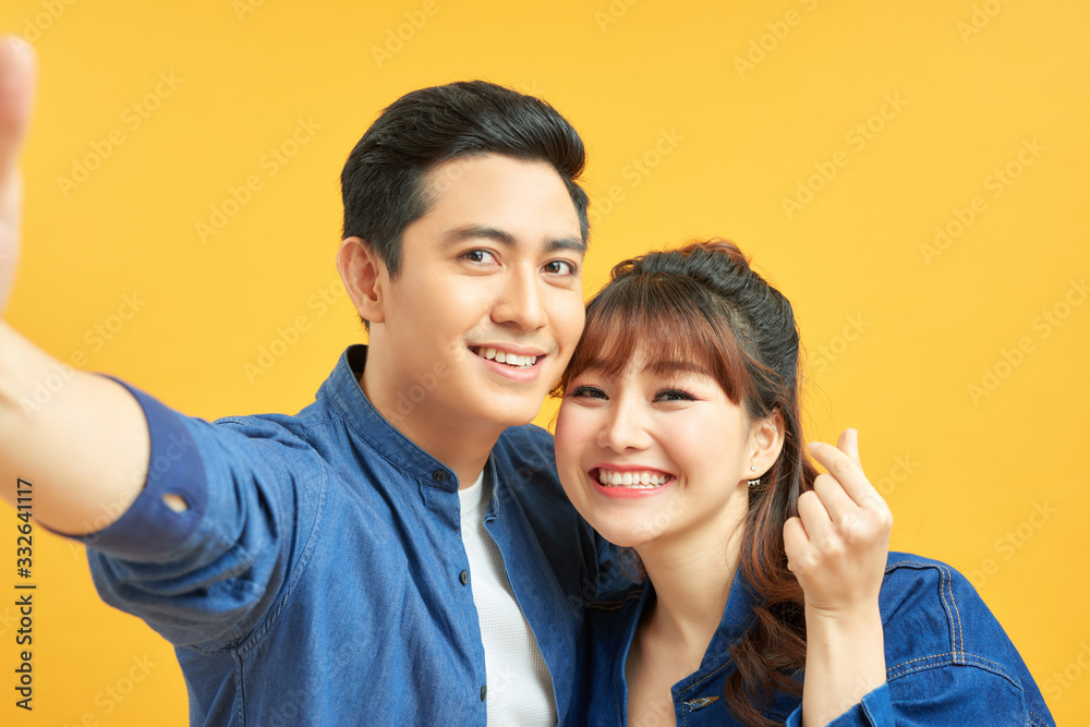 Self portrait of funny foolish cheerful adorable young cute couple smiling showing teeth, looking straight with opened mouths over yellow background, isolated Self portrait of funny foolish cheerful adorable young cute couple smiling showing teeth, looking straight with opened mouths over yellow background, isolated