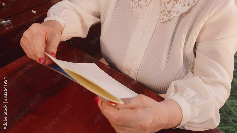 Old lady puts handwritten letter into envelope. Up view. Old way of sending mail.