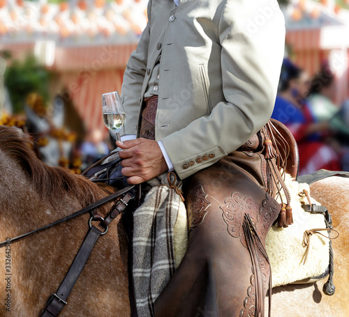 Fototapeta Rider on horseback dressed in traditional costume and holding glass of fino sherry (manzanilla sherry) at the April Fair (Feria de Abril) Andalusia, Spain