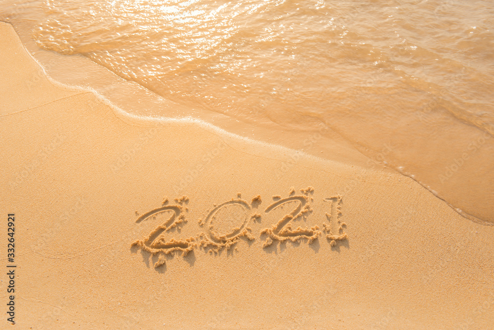 Fototapeta premium lettering on the beach with wave. Numbers 2021 year on the sea shore, message handwritten in the golden sand on a beautiful beach background. Happy new years 2021 concept.