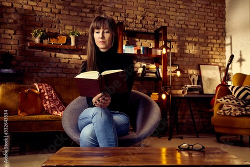 young woman reading a book at home