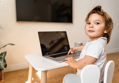 Toddler girl using laptop on her table. Top view. Online education 