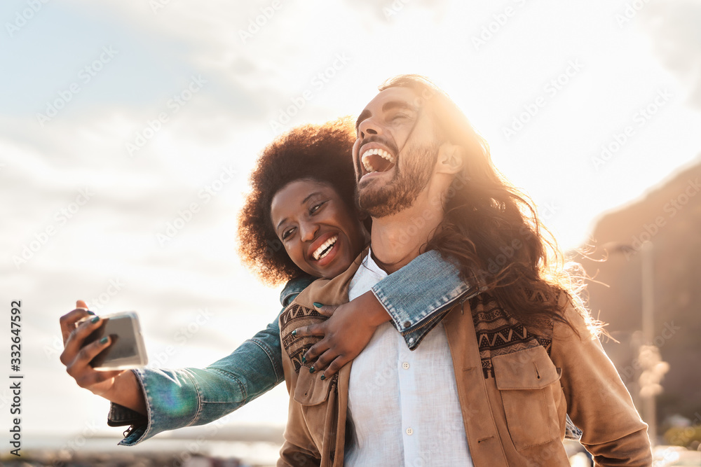 © Alessandro Biascioli - Happy smiling couple taking selfie with mobile smartphone outdoor - Young trendy people having fun during vacations - People technology addicted and travel trend lifestyle concept