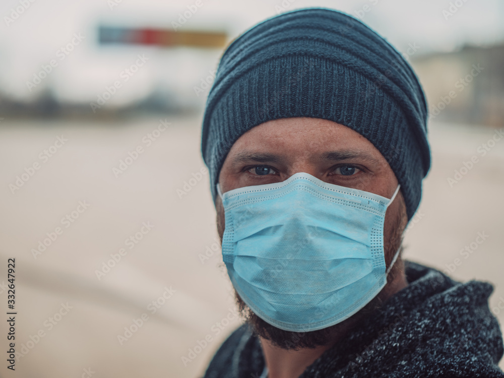 Close Up Portrait Of A Hipster Man In A Medical Mask For Protection Against Influenza Virus Or Coronavirus Outdoor. Corona Virus Pandemic. Epidemic Viral Respiratory Syndrome. 2019-nCoV
