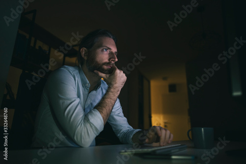 Bearded man working long hours on computer from his home