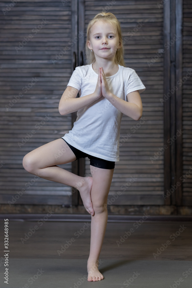 girl child doing exercises doing yoga on a Mat in the Studio or at home . the child is engaged in physical education stretching and training