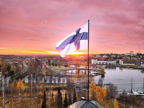 Aerial view of Finnish flag on the tower of Town Hall against the red sunrise sky in Joensuu, Finland. photo