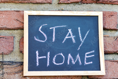 Schild mit dem handgeschriebenen Hinweis „zu Hause bleiben“ in englischer Sprache (stay home)