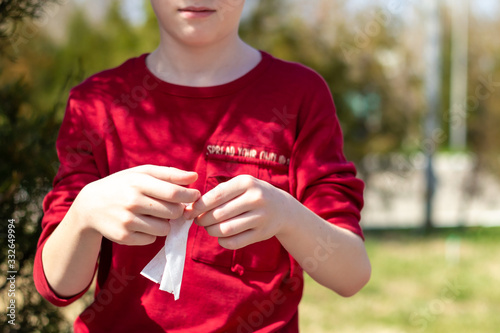 the kid in red t-shirt clean his hands with antibacterial wipe