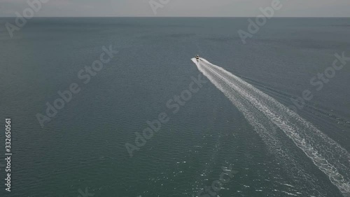 Speed boat sailing off whilst drone cases after it.