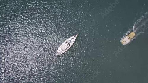 Top Down Aerial of a sailing Yacht as the camera turns 360 degrees. A motorboat also passes by, whilst the camera turns