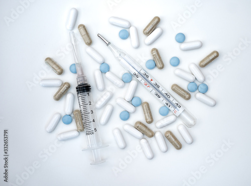 pills syringe and thermometer on white background
