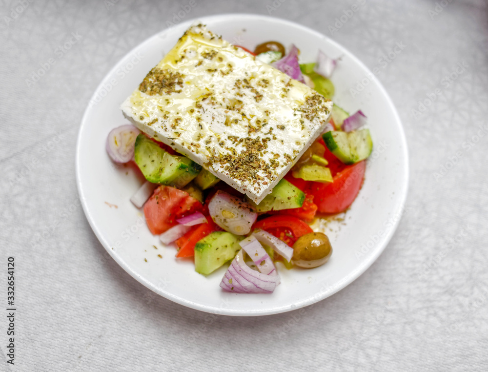 Greek salad plate with entire piece of original feta cheese, top view close up