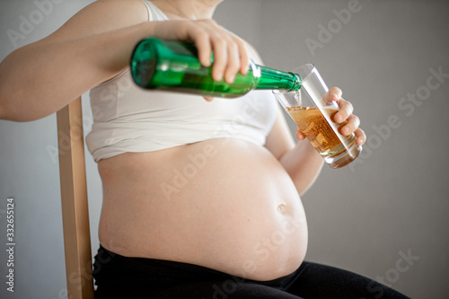 pregnant woman pours a beer, glass is almost full photo