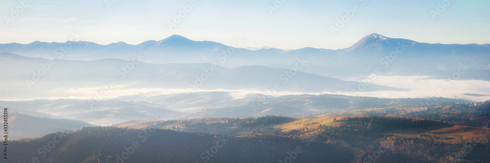 Panorama alpine landscape of the mountain peaks and valleys covered in fog at dawn. Spring  landscape mountains and colorful forest on background sunrise.