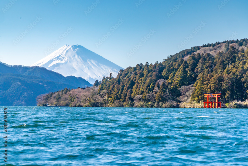 mt.fuji and red torii gate viewed from the shores of lake ashi,