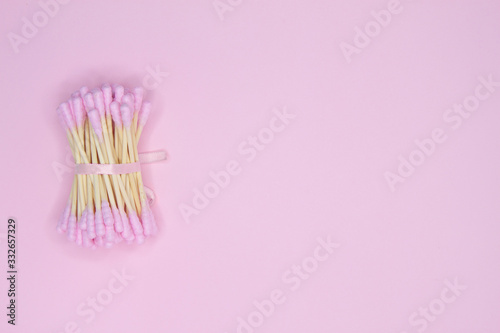 Flat layout of pink cotton buds on pink background