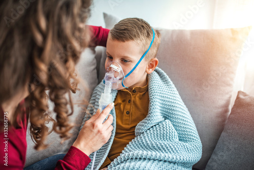 фотографія Woman with son doing inhalation with nebulizer at home