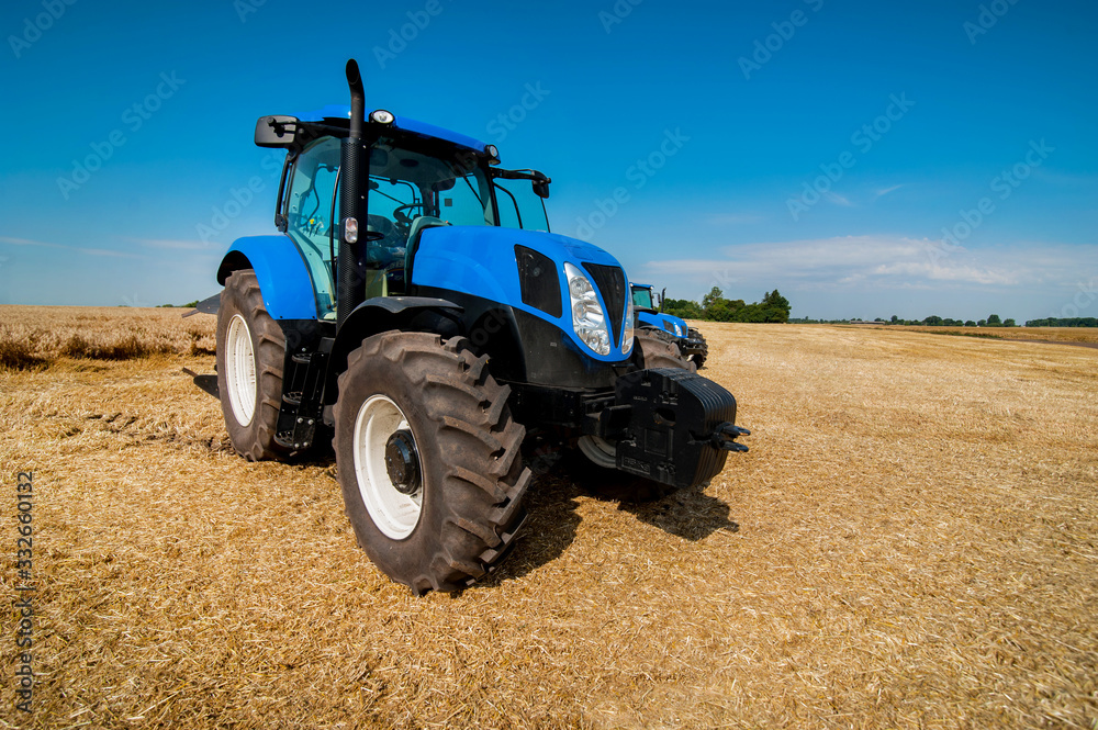 New blue tractor working on the field, modern agricultural transport New blue tractor working on the field, modern agricultural transport