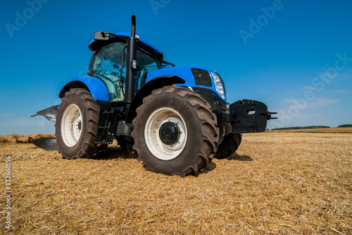 New blue tractor working on the field  modern agricultural vehicle