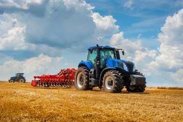 Acrylglasbilder Traktor Blauer Traktor mit Egge im Feld  © pavlobaliukh