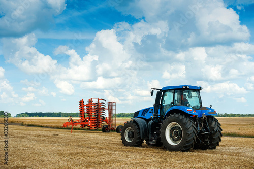 blue tractor and red harrows, arable land, field preparation