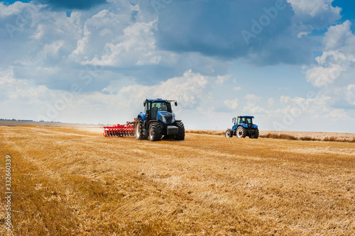 Fotografie, Obraz two blue tractors pulls harrows preoparate arable land, field and beautiful clou